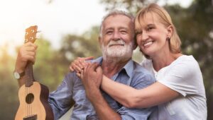 Older female and male model embracing outside with instrument