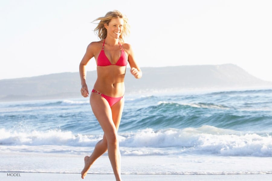 Female in red bikini running on beach | Westfield Plastic Surgery Center Female in red bikini running on beach